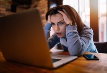 Woman frustrated at laptop, holding her head.