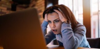 Woman frustrated at laptop, holding her head.