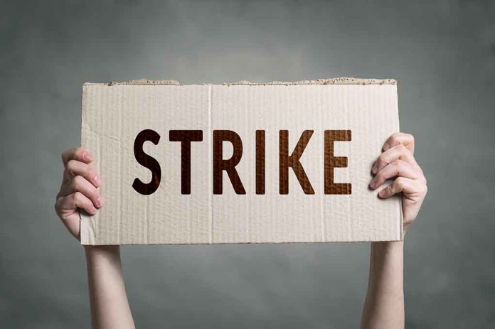 Two hands holding a cardboard sign saying strike