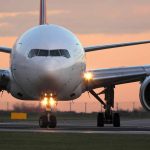 Airplane on runway during sunset, lights on.