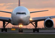 Airplane on runway during sunset, lights on.