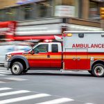 Ambulance speeding through city street intersection.