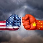 Fists painted like USA and China flags facing off