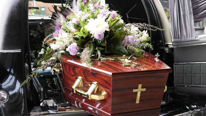 Coffin with flower arrangement in a hearse.