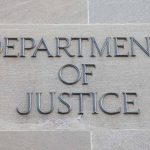 Department of Justice sign on building wall.