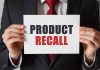 "Product Recall" sign held by person in suit.