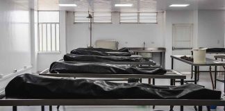 Covered bodies on metal tables in a morgue.