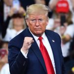 Man in suit making a fist gesture at rally.