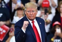 Man in suit making a fist gesture at rally.