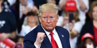 Man in suit making a fist gesture at rally.