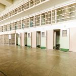 Empty prison cells with open doors, two-story layout.