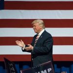 Man clapping in front of American flag background