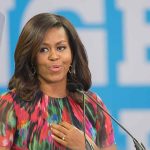 Woman speaking at podium with blue background.