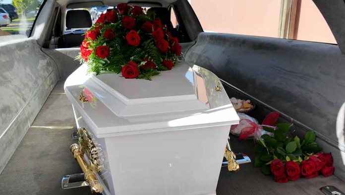 White coffin with red roses inside a hearse.