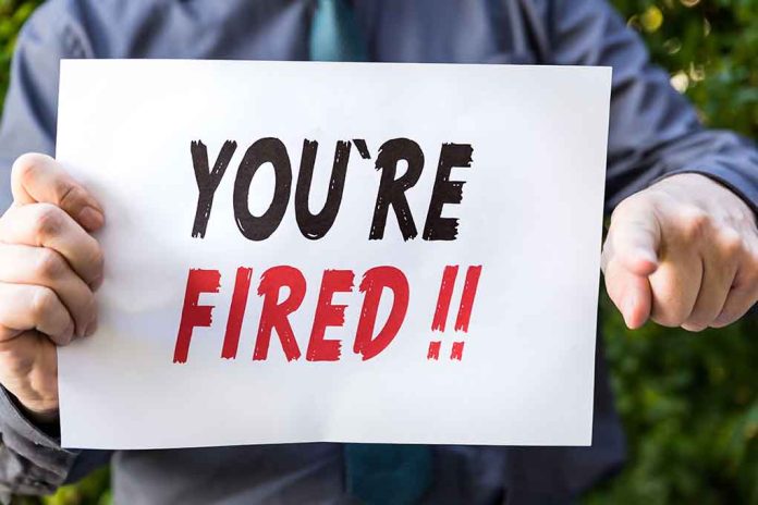 Person holding "YOU'RE FIRED" sign.