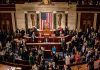 Crowded legislative chamber with people in discussion