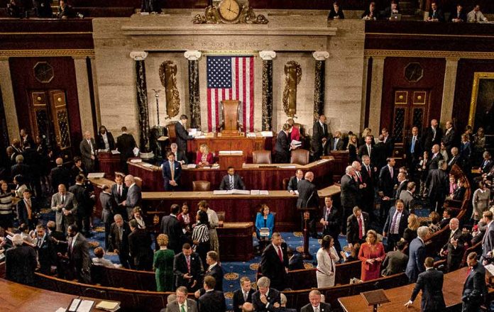 Crowded legislative chamber with people in discussion