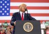 Man speaks at podium with U.S. flag background.