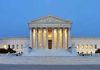 Large neoclassical building with illuminated columns at dusk