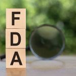 Wooden blocks spelling FDA with magnifying glass nearby
