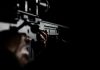 Person holding a rifle in dim lighting