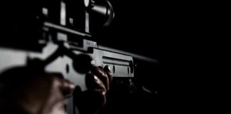 Person holding a rifle in dim lighting