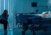 Woman sitting beside hospital bed at night