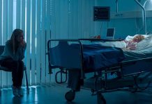 Woman sitting beside hospital bed at night