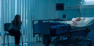 Woman sitting beside hospital bed at night