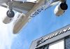Airbus plane flying over Boeing building