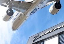 Airbus plane flying over Boeing building