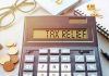Calculator display reads TAX RELIEF amidst coins and glasses