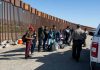 Group of people at border wall with patrol agents