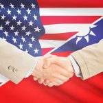 Two people shaking hands with USA Taiwan flags