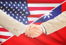Two people shaking hands with USA Taiwan flags