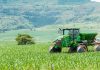 Green tractor working on a lush field landscape