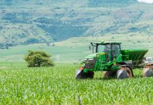 Green tractor working on a lush field landscape