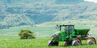 Green tractor working on a lush field landscape
