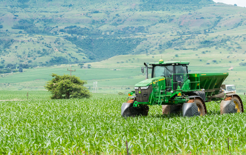 Green tractor working on a lush field landscape