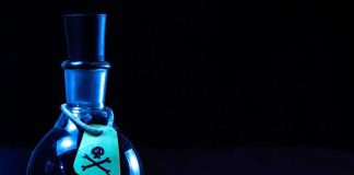 Dark bottle with skull and crossbones label on table
