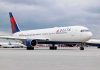 Delta Airlines airplane on airport runway, cloudy sky
