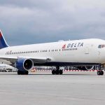 Delta Airlines airplane on airport runway, cloudy sky