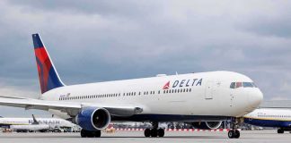 Delta Airlines airplane on airport runway, cloudy sky