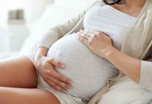 Pregnant woman holding her belly sitting comfortably