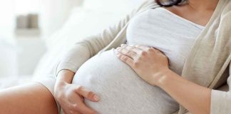 Pregnant woman holding her belly sitting comfortably