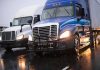 Two trucks driving on a wet road