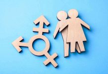 Wooden transgender symbol and couple figures on blue background