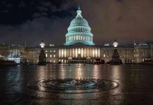 U.S. Capitol building illuminated at night with wet pavement.