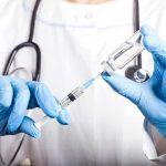 Doctor filling syringe with vaccine from vial