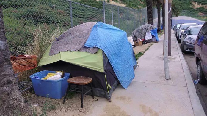 1392494762 Tents and belongings set up along sidewalk